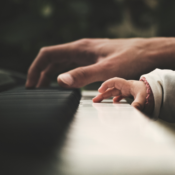 Bild von zwei Händen am Klavier (Erwachsenen- und Kinderhand)