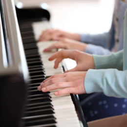 Bild von zwei Schüler:innen vierhändig spielend am Klavier